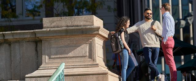 Three students speak at the top of the stairs outside Jerome Greene