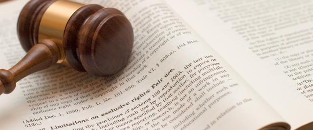 A gavel lies on top of an open legal dictionary.